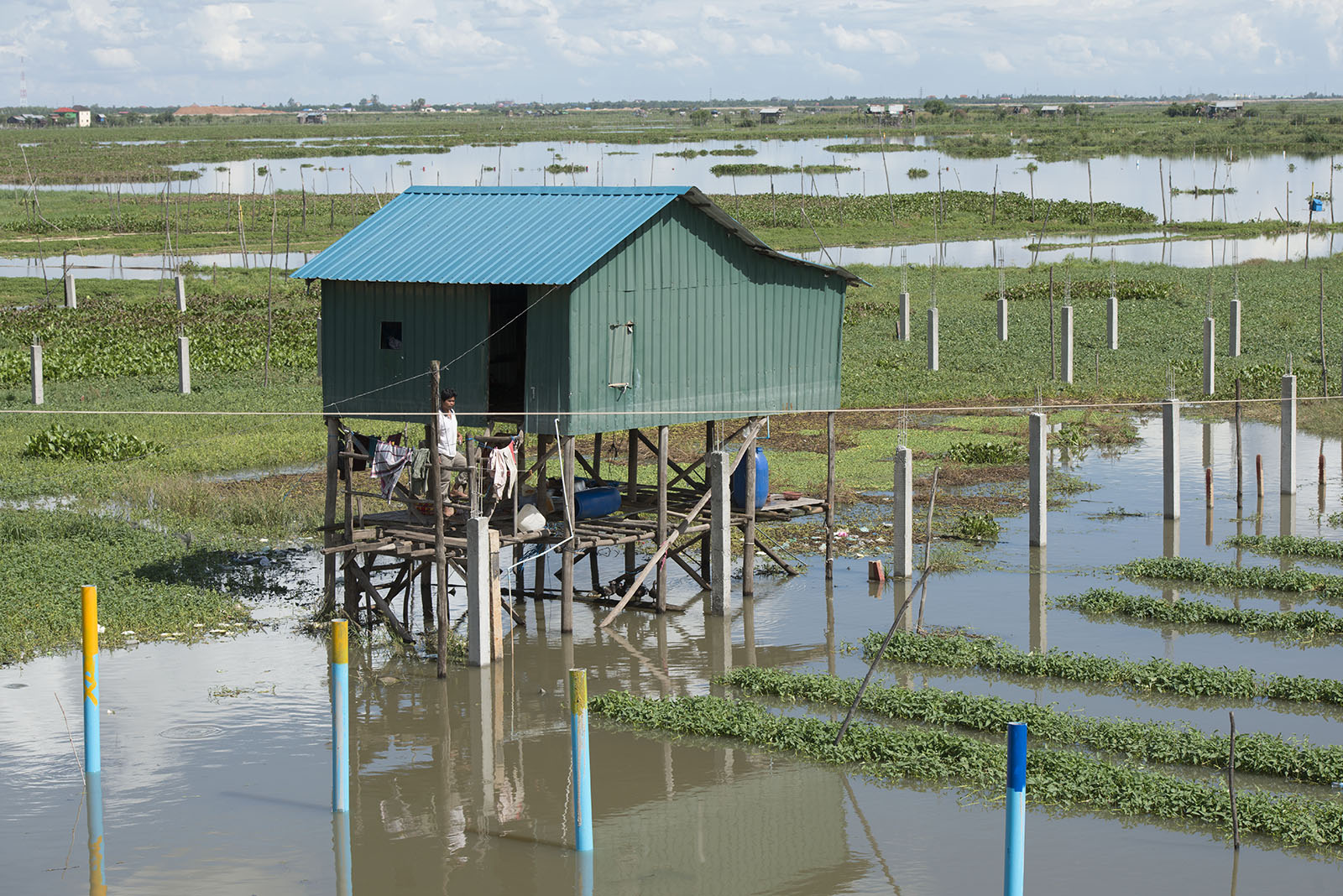 A farmer standing outside his stilt home on farmland in Phnom Penh, Cambodia