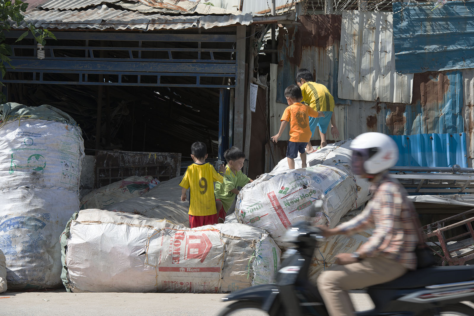 Children playing on big bags with plastic bottles for recycling on the roadside in Phnom Penh, Cambodia