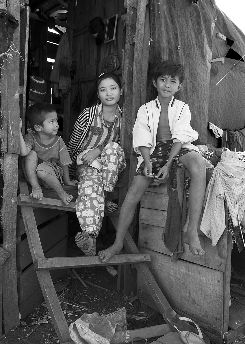 Cambodian children sitting on the doorsteps to there wooden home, a small room for the entire family